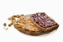 A slice of bread spread with peanut butter and another spread with jam