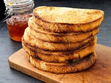 A stack of toast on a chopping board with jam