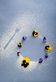 A fork print in icing sugar and round biscuits decorated with pansies