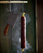 A raw sausage hanging in a smoking chamber