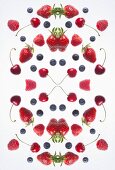 A digital composite of mirrored images of various berries and cherries