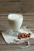 A glass of almond milk with almonds next to it