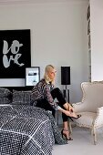 Young woman sitting on bed with graphically patterned bedding