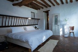 Rustic wooden ladder above head of double bed in bedroom