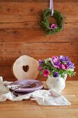 Bouquet of anemones in rustic milk jug and stacked plates on table