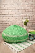 Crocheted green pouffe on green and white rug