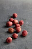 Lychees scattered on a grey stone surface