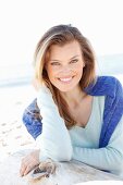 A young woman on a beach with a jumper over her shoulders