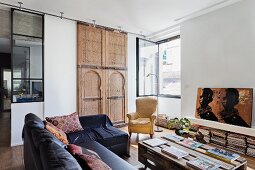 Pallet table and black leather sofa in a living room with Moroccan artisan wooden element