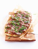 Pizza with pancetta and rocket on a wooden board