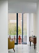 Study with view through glass wall onto terrace with classic wire mesh chairs