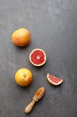 Pink grapefruits, whole and halved, with a wooden juicer (seen from above)