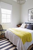 Gelbe Tagesdecke auf Doppelbett in schlichtem Schlafzimmer