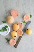 Guavas, whole and halved, on a grey surface