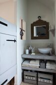 White modern basin on concrete washstand counter with concrete shelf and vintage wooden crates below