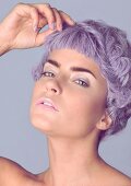 A young woman with pastel coloured make up wearing a short purple wig