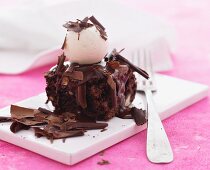 A slice of chocolate cake with a scoop of vanilla ice cream and grated chocolate