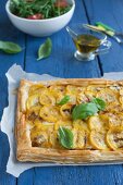 A puff pastry tart with yellow courgettes, pesto rosso, cheese and basil