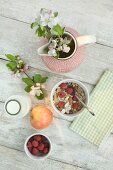 Muesli with nuts, apples, raspberries and milk on a wooden table (seen from above)