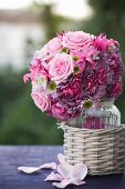 Romantic bridal bouquet of pink roses in glass vase in wicker pot
