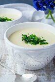 Potato soup with green asparagus and chives in ceramic bowls
