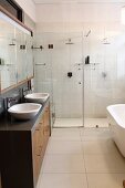 Designer bathroom with twin sinks, mirrored wall cabinet and two rainfall showers behind glass partition