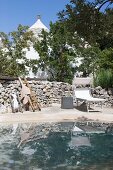 Sun loungers in front of stone wall next to pool outside trullo