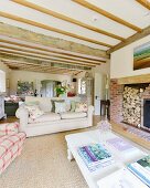 White-painted coffee table and sofa in front of fireplace with firewood store in rustic interior