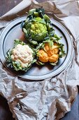 Various different coloured cauliflowers on a pewter plate