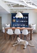 Wooden table, white Eames chairs and blue-painted dresser in renovated country-house interior with Labrador lying on floor