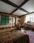 Twin beds and dressing table below window in traditional bedroom with exposed ceiling beams