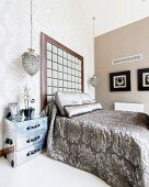 Tagesdecke mit Ornamentmuster auf Doppelbett, an Wand hohes Kopfteil in eleganter Schlafzimmerecke