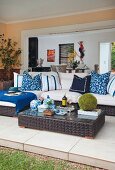 Dark, wicker outdoor furniture; low table and sofa with blue and white patterned cushions on tiled living room terrace