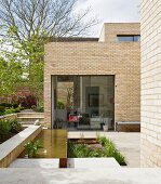 Geometric terrace with flowerbed and pool outside modern brick house
