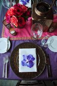 Festive place setting with orchid bloom on table set for Indian wedding