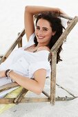A brunette woman sitting in a deck chair wearing a white T-shirt