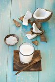 A glass of coconut milk, a broken coconut and grated coconut