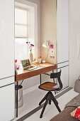 Drehbarer Bürostuhl aus Holz vor minimalistischem Schreibtisch am Fenster