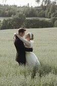 A young bride and groom hugging in an oat field