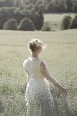 A young bride walking through an oat field