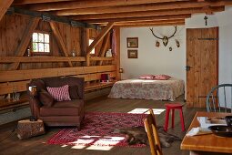 Open-plan interior with seating and double bed in rustic wooden house