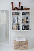 Collection of whiskies in wall-mounted cabinet above wicker trunk
