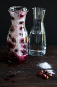 Ingredients for cherry liqueur (alcohol, sour cherries, sugar) in a carafe, alcohol being added