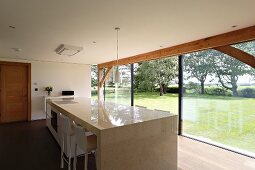 Freistehende Küchentheke aus poliertem Stein, Panoramaverglasung und Blick in Garten