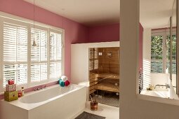 Bathtub below window in spacious bathroom with sauna