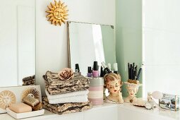 Stacked towels and makeup utensils on shelf with vintage accessories