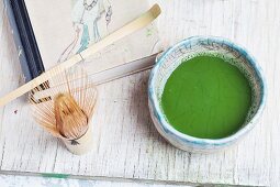 Matcha in a bowl (chawan), next to a bamboo whisk (chasen) and a spoon (chashaku)