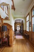 Foot of staircase and long hallway with panelled wainscoting in elegant villa