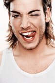 A young man wearing a white undershirt pulling a face