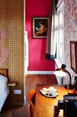 Schreibtisch im Schlafzimmer, im Hintergrund Durchgang und Blick auf Bild an pinkfarbener Wand